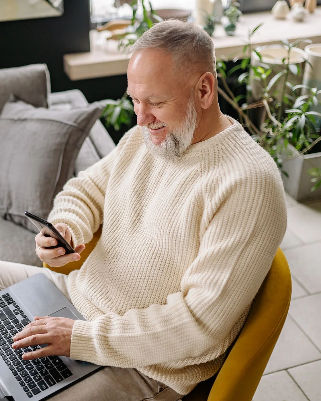 A man checking product reviews on his phone and laptop at home